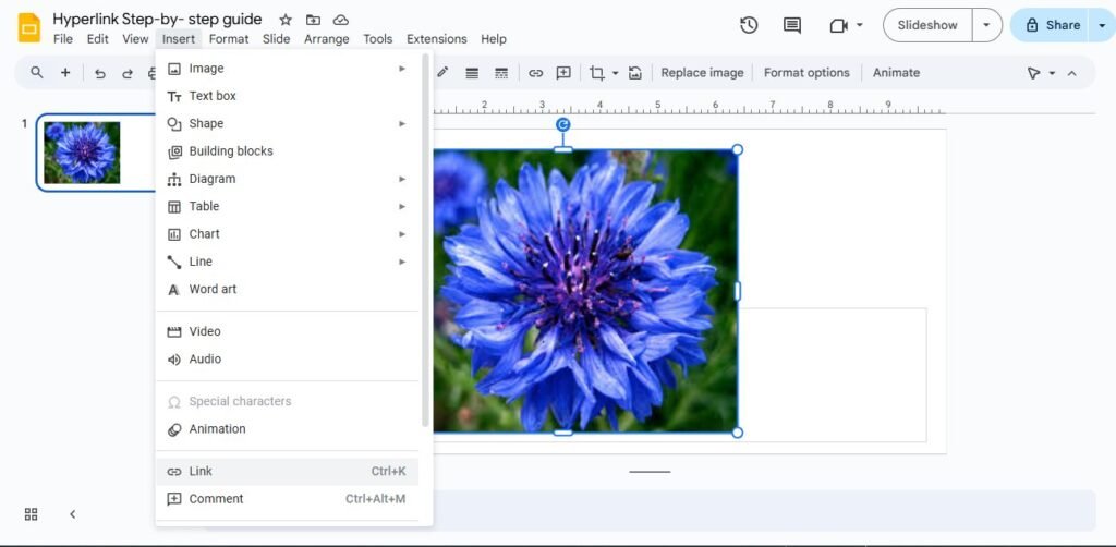 A screenshot of a Google Slides presentation with a blue flower image selected, and the "Link" option is visible in the Insert menu.